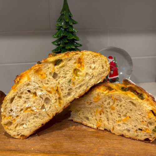 cheddar jalapeno sourdough bread loaf cut in half to show the crumb.