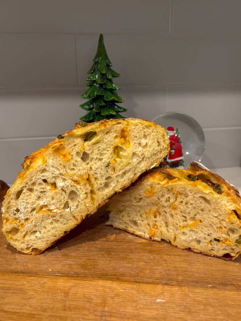 cheddar jalapeno sourdough bread loaf cut in half to show the crumb.