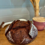 Whole chocolate sourdough bread loaf with deep scoring and a rich, dark crust on a wooden board
