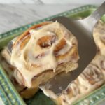 Close-up of a gooey sourdough discard cinnamon roll topped with brown butter vanilla bean frosting