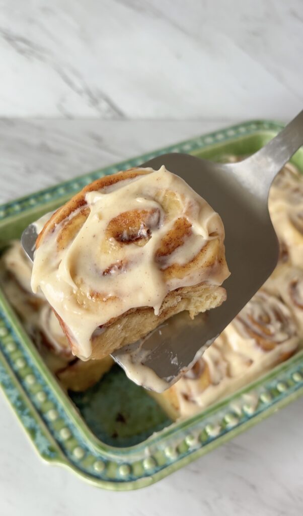 Close-up of a gooey sourdough discard cinnamon roll topped with brown butter vanilla bean frosting